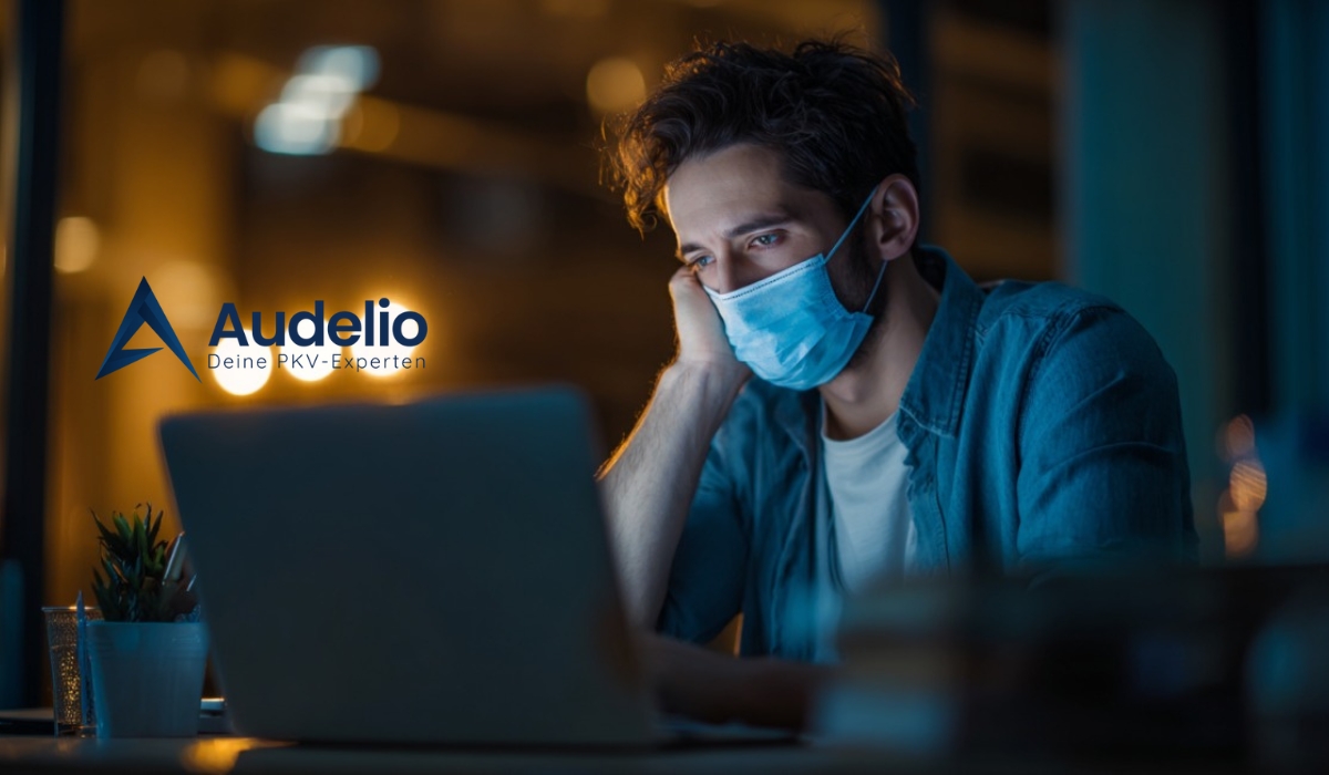 Ein Mann mit Gesichtsmaske arbeitet spät abends am Laptop, neben ihm das Logo von Audelio mit dem Slogan „Deine PKV-Experten“